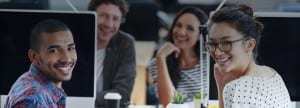 Coworkers sitting with computers and smiling