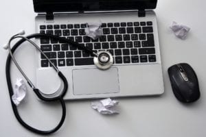 Computer with stethoscope and crumpled up papers