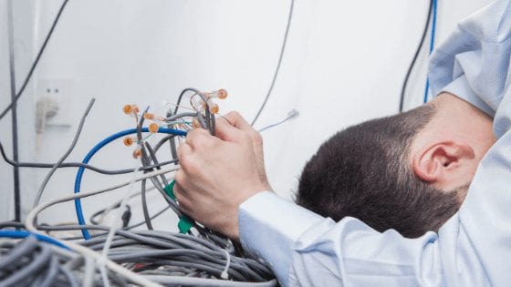 Frustrated man with head bent holding computer wires