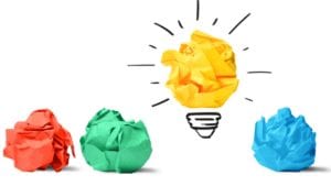 four crumpled balls of paper with one yellow ball made to look like a light bulb